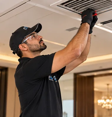 Technician removing a ceiling AC diffuser to clean the duct